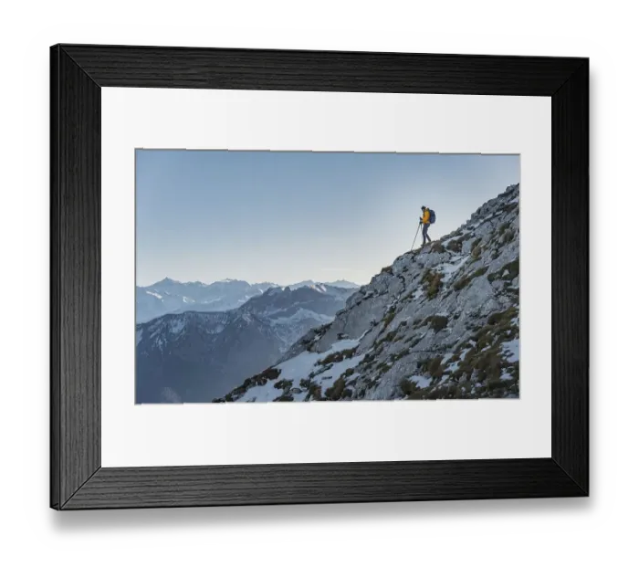 Framed Print : Climber on a ledge, snow-covered mountains