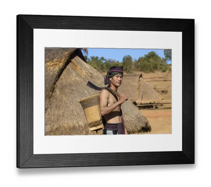 Framed Print : Man in traditional costume in front of a Phnong house
