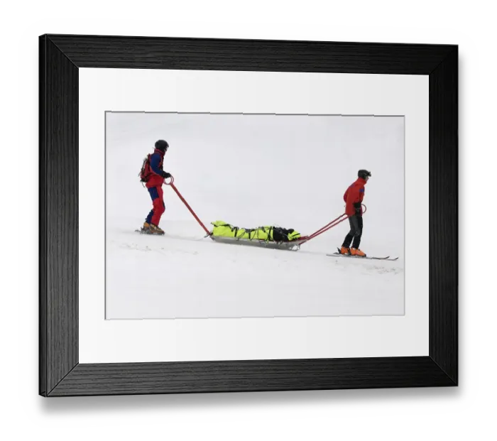 Framed Print : Mountain rescue service, two helpers taking an accident victim in a rescue sled into the valley