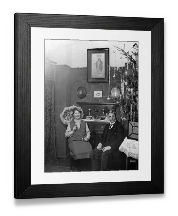 Framed Print : Couple celebrates Christmas in the living room next to the Christmas tree Framed Print : Couple celebrates Christmas in the living room next to the Christmas tree