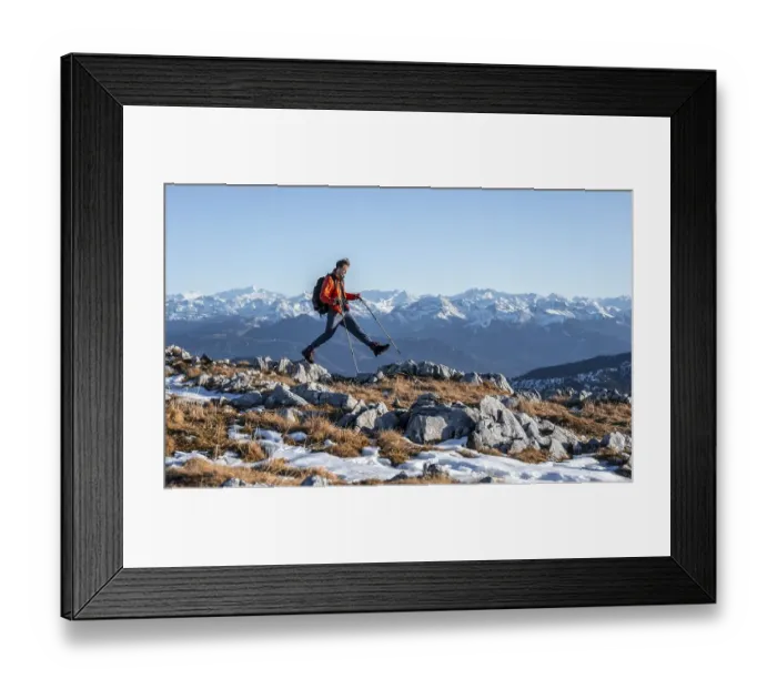 Framed Print : Mountaineer taking a big step, in front of mountain panorama