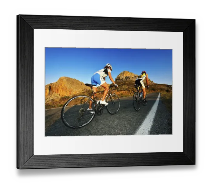 Framed Print : Two racing cyclists cycle uphill on the road