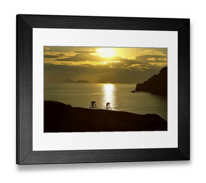 Framed Print : Two mountain bikers cycling on a rocky coast