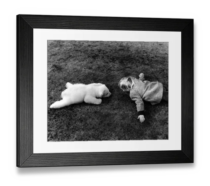 Framed Print : Little polar bear and a girl lying on the meadow