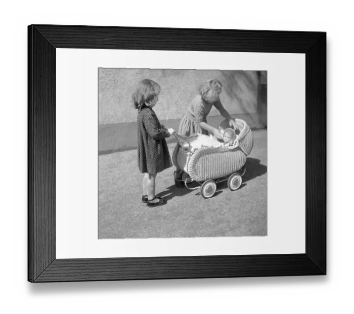 Framed Print : Two children play with a doll in a pram