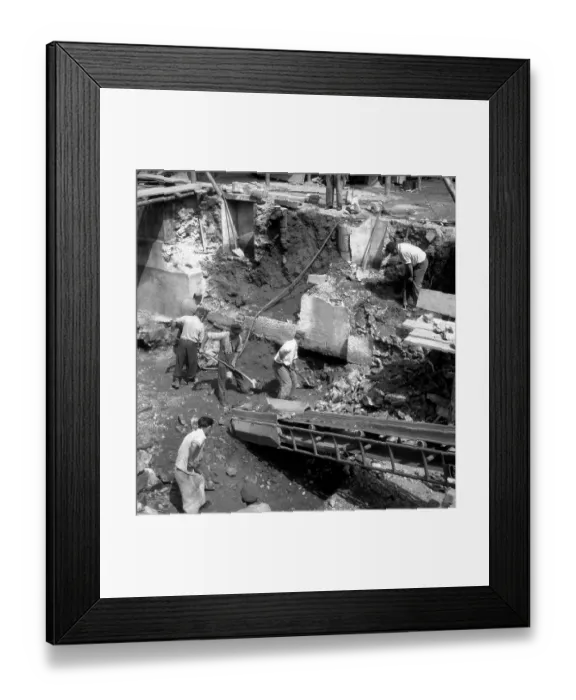 Framed Print : Construction workers shovel earth out of a hole