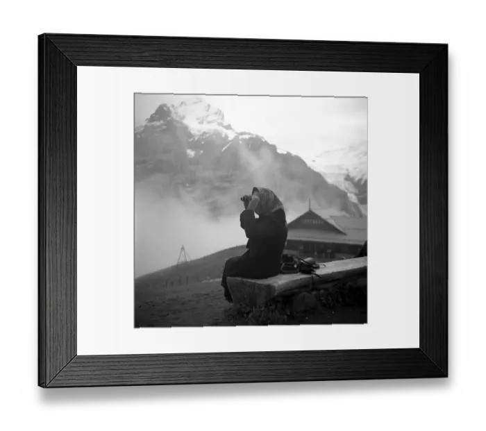Framed Print : An elderly woman sits in the mountains on a wooden bench and examines the landscape through binoculars