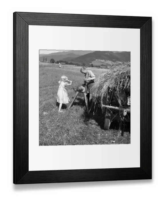 Framed Print : Man standing at the grindstone and girl cranked