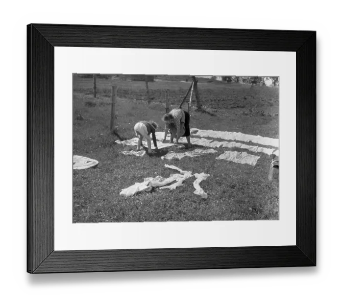 Framed Print : Mother and child put the laundry on the lawn and in the sun