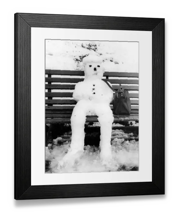 Framed Print : Snowman nit bag sits on bench ca