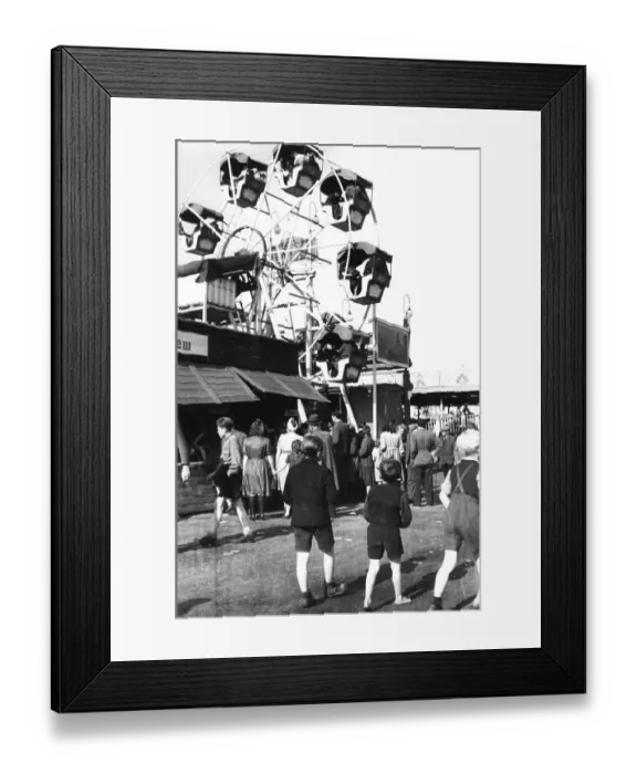 Framed Print : People walk over the fairground and look at the ferris wheel