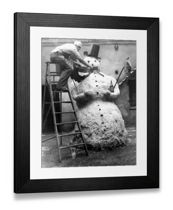 Framed Print : Man adorns big snowman, ca. 1955
