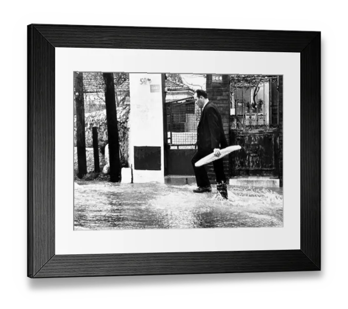 Framed Print : Man carrying a baguette through a flooded street