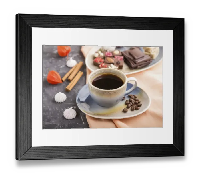 Framed Print : A cup of coffee with chocolate and coconut candies on a black concrete background and orange textile