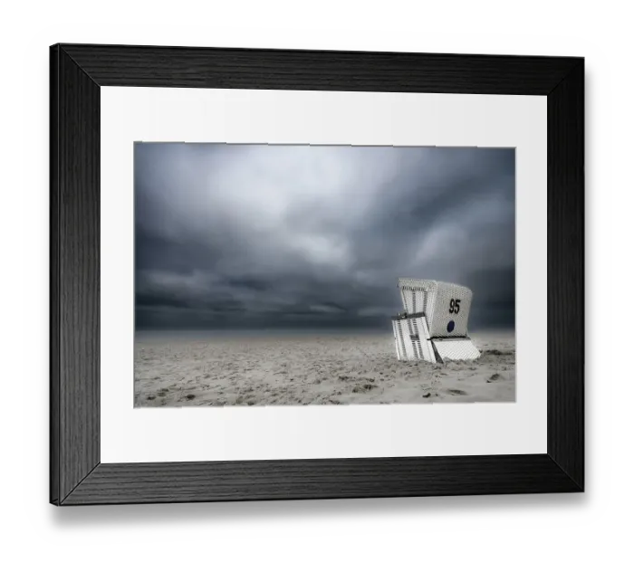 Framed Print : Beach chair in front of dark cloudy sky