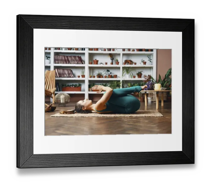 Framed Print : Young woman lying on the back with his knees doing twisting exercise at home