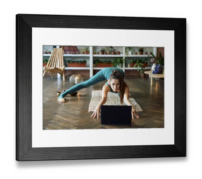 Framed Print : Young sporty woman practicing yoga at home watching online exercises on her laptop Framed Print : Young sporty woman practicing yoga at home watching online exercises on her laptop