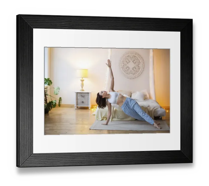 Framed Print : Smiling young brown haired woman in pajamas practicing yoga in bright bedroom in the morning