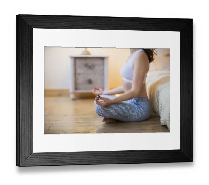 Framed Print : Smiling young brown haired woman in pajamas practicing yoga in bright bedroom in the morning