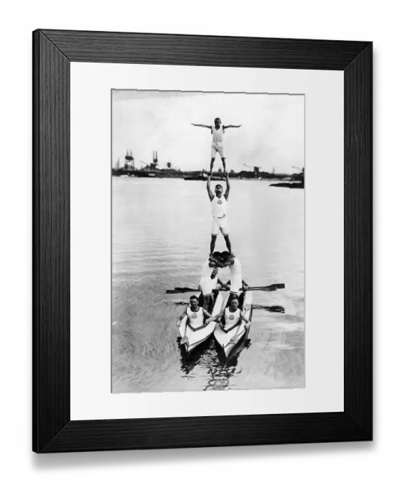 Framed Print : Acrobats build a pyramid on two rowing boats in the water