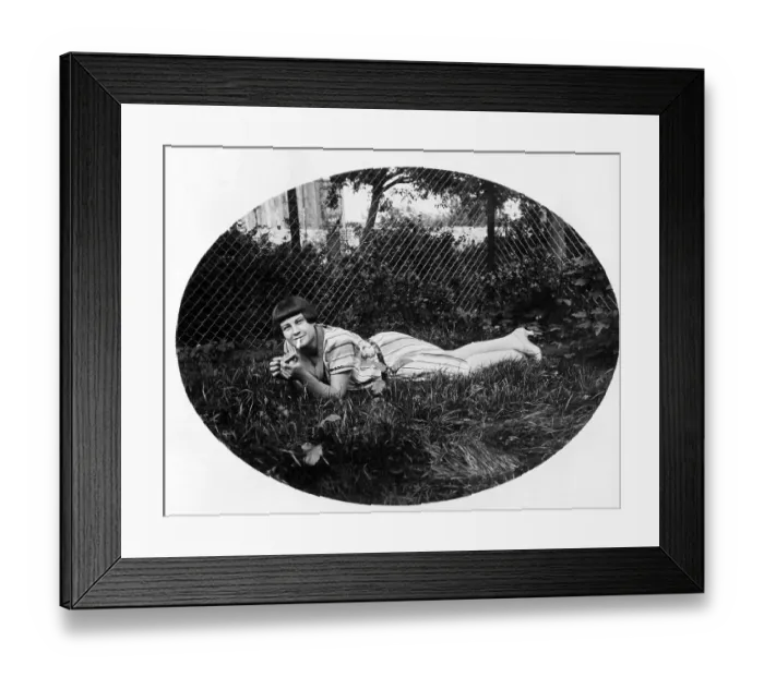 Framed Print : Young woman lying in the grass smoking