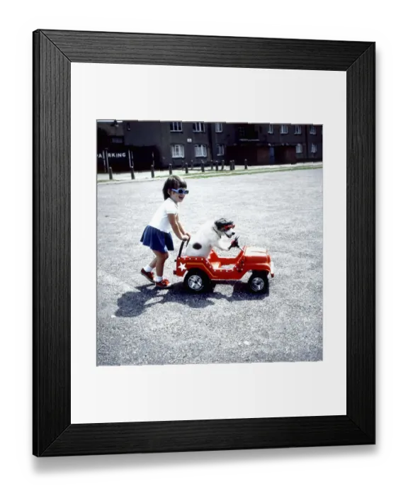 Framed Print : Girl pushes Jack Russell in toy car Framed Print : Girl pushes Jack Russell in toy car