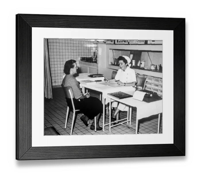 Framed Print : Old black and white archival photograph showing female factory worker visiting nurse at dispensary in the 1950s