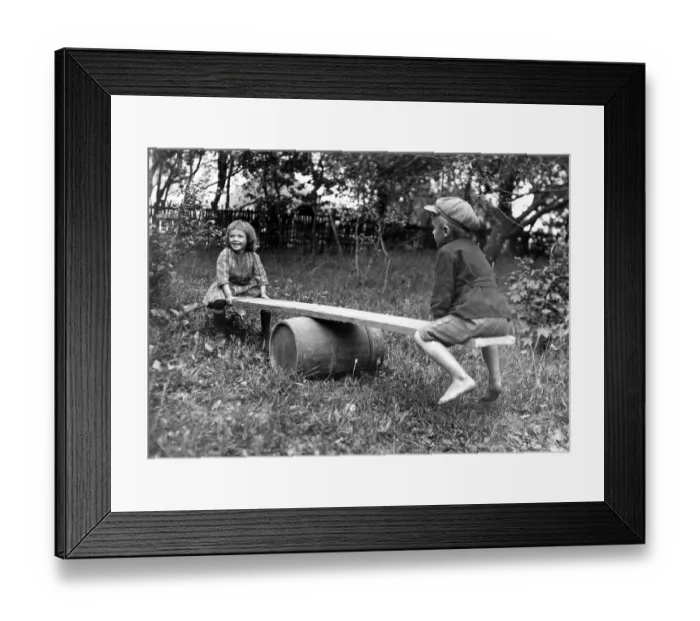Framed Print : Historic photograph, two children on a seesaw in the garden