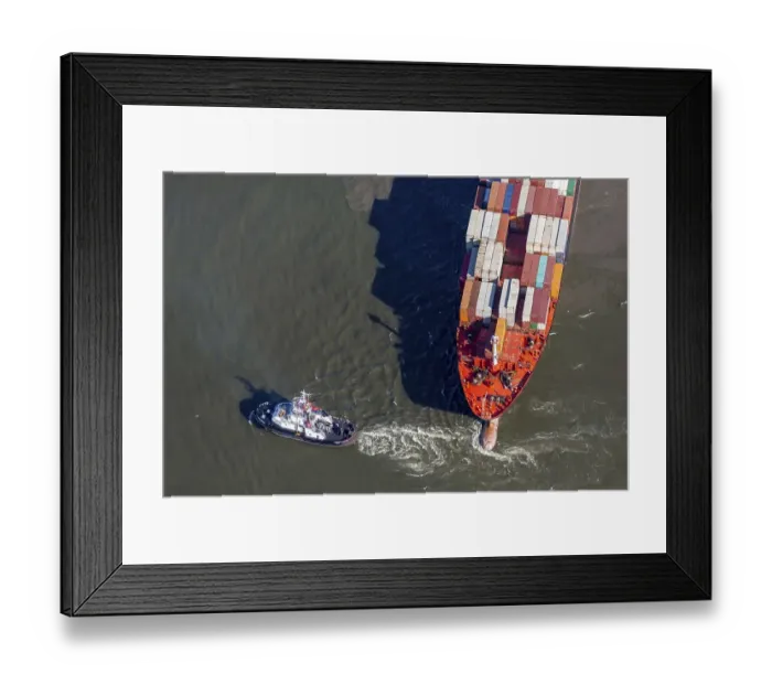 Framed Print : Aerial view of a tugboat pulling a container ship on the Elbe and giving direction
