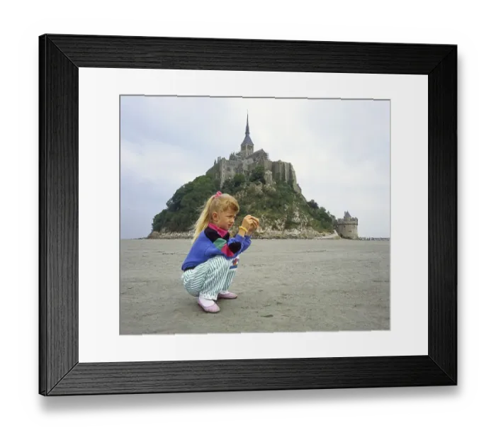 Framed Print : Little girl, age 7, examines what she found on the seabed in front of Mont Saint Michel
