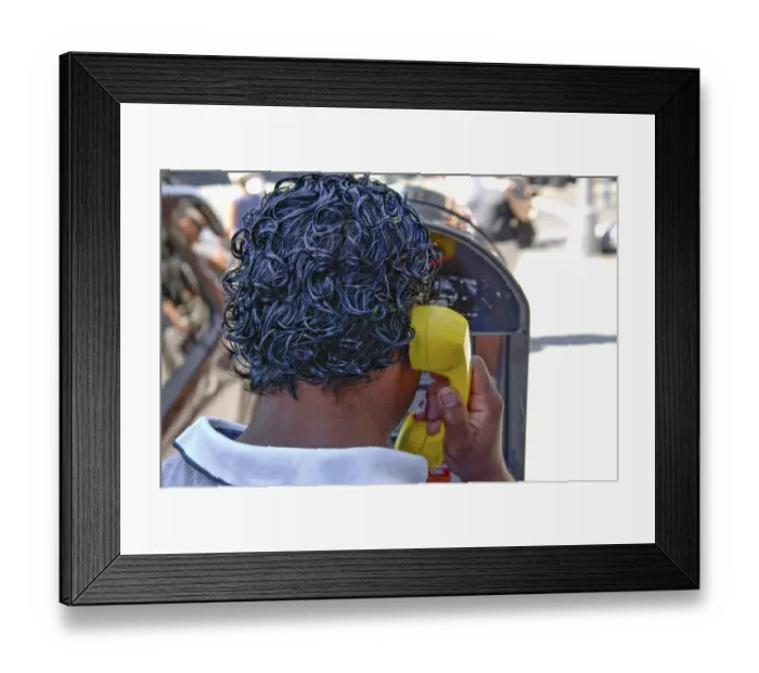 Framed Print : Black-haired New Yorker making a phone call at a telephone pillar with yellow handset
