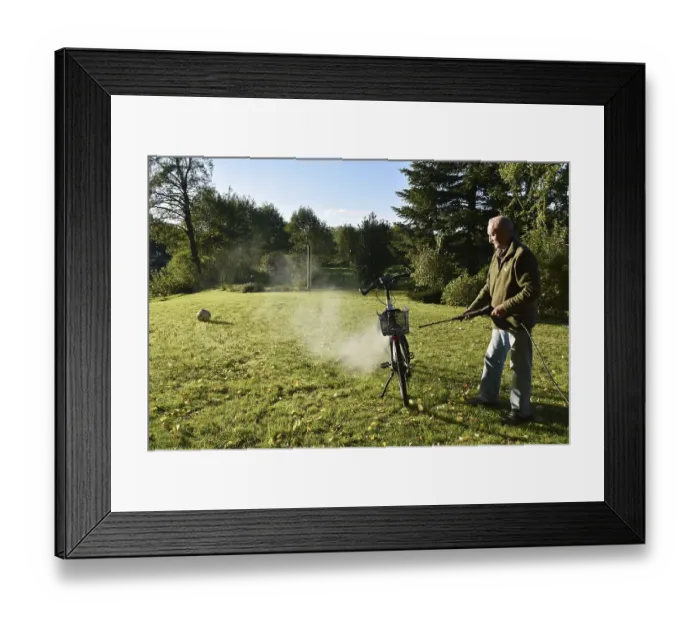 Framed Print : Man cleans bicycle with high-pressure cleaner