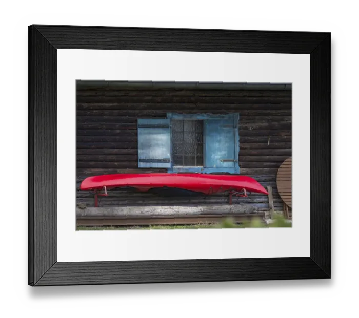 Framed Print : Red kayak boat hanging from a wooden hut with blue shutters Framed Print : Red kayak boat hanging from a wooden hut with blue shutters