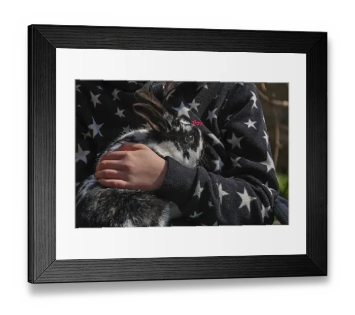 Framed Print : Child's hand holding black and white hare on black and white jacket