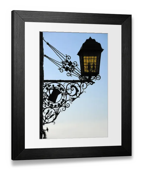 Framed Print : Old, wrought-iron inn sign as a silhouette on the castle building