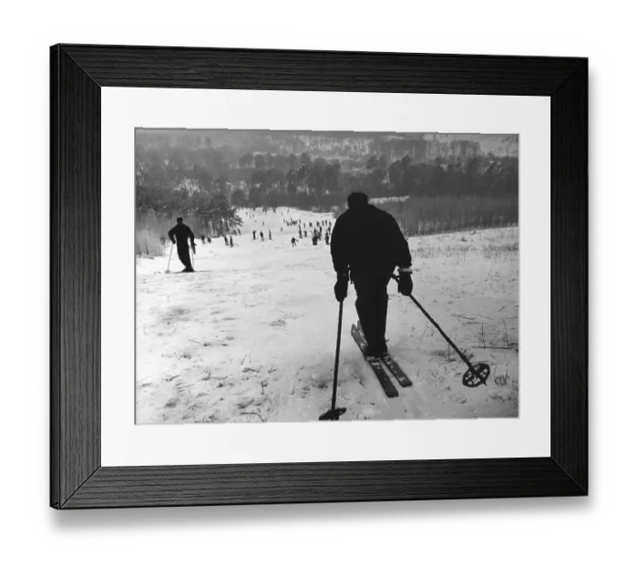 Framed Print : Winter sports, man drives down the slope and looks into a valley full of skiers