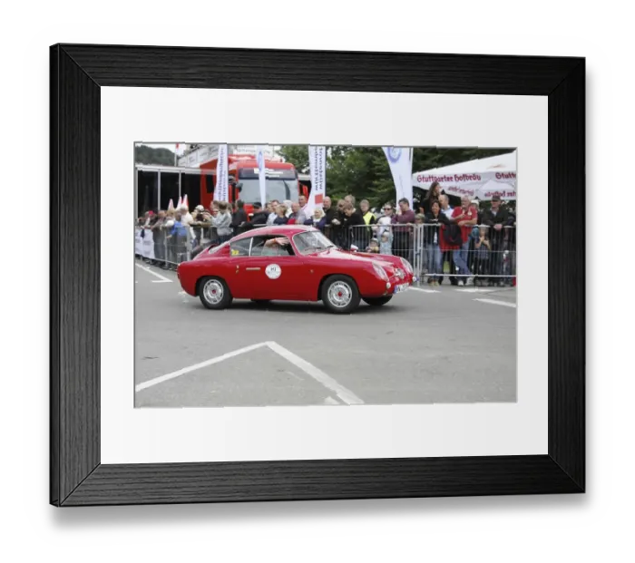 Framed Print : A red vintage car during a rally on the race track in front of spectators