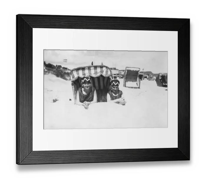 Framed Print : Holiday, two women lying on the beach in front of a beach chair