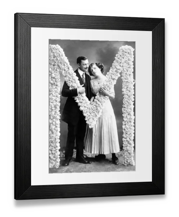 Framed Print : Flirt, man and woman stand at the letter M build from roses
