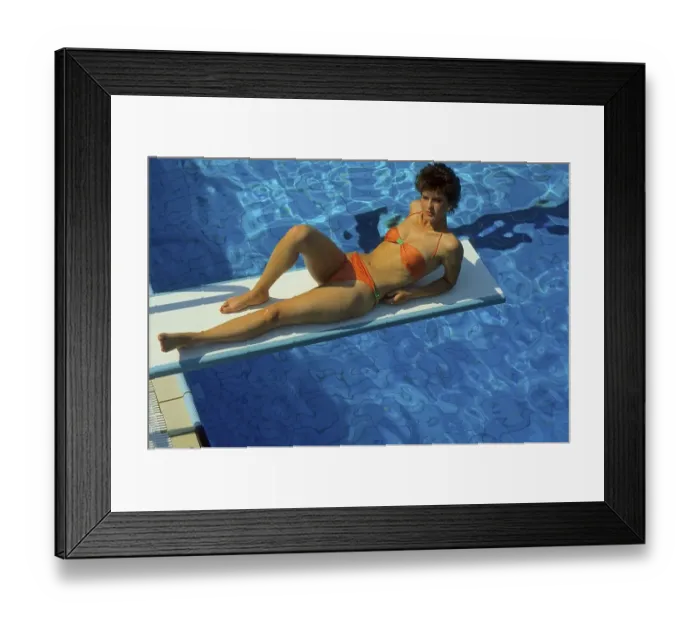 Framed Print : Young woman in bikini lying on the diving board at the swimming pool
