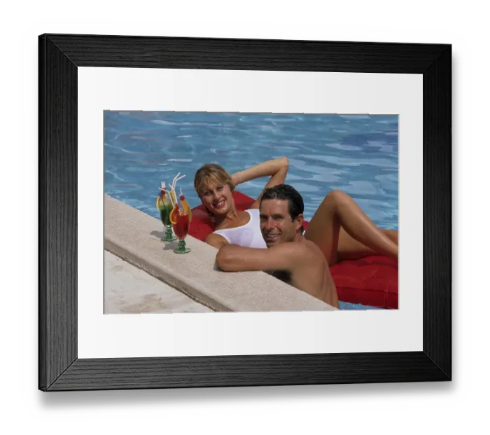 Framed Print : Young couple at the pool, woman lying on air mattress man at the edge of the pool