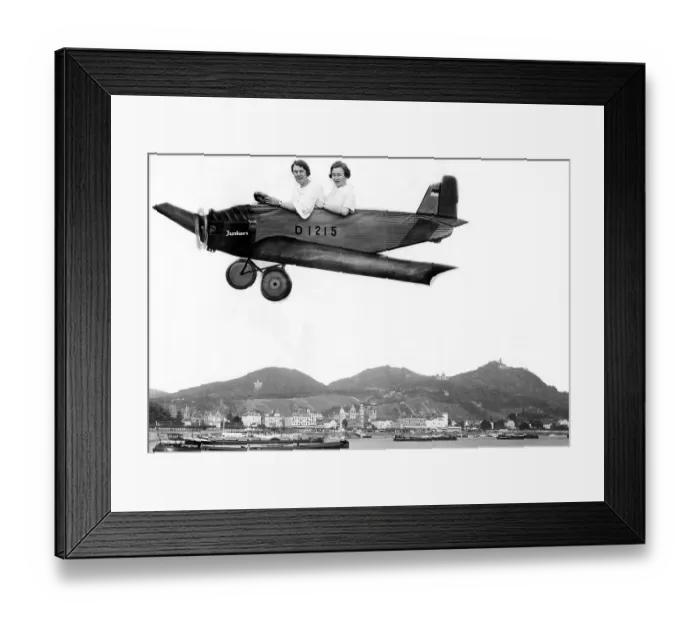 Framed Print : Two women fly into a cardboard plane over the Rhine