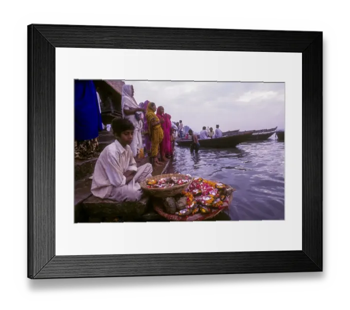 Framed Print : A boy selling mari gold flowers used in workship sitting in front of River Ganga Ganges at Varanasi Benaras