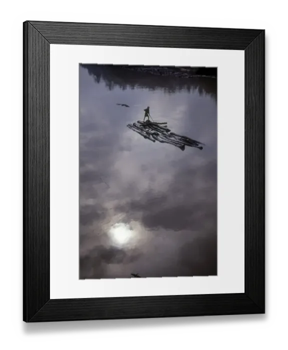 Framed Print : A man rowing on few wooden logs