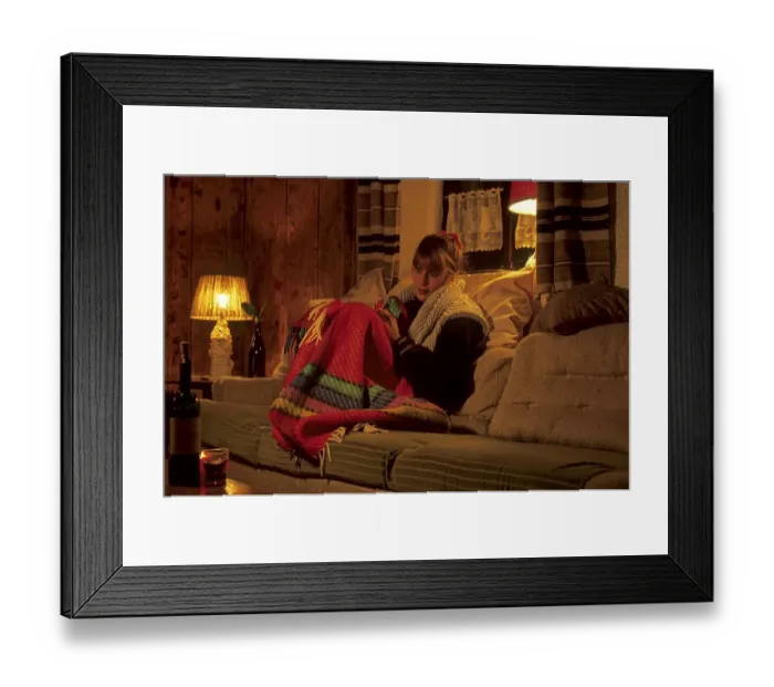 Framed Print : Young woman warmly dressed in the flat with blanket on the couch