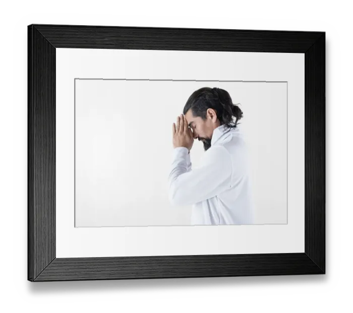 Framed Print : A man dressed in white clasping hands while meditating over white background