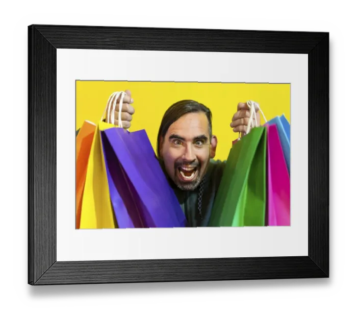 Framed Print : Close-up of a crazy man holding colorful shopping bags over yellow background Framed Print : Close-up of a crazy man holding colorful shopping bags over yellow background