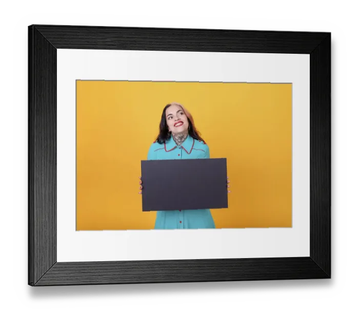 Framed Print : Beautiful woman holding a blank sign against a yellow background