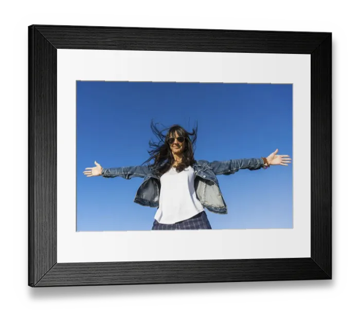 Framed Print : Low angle view of a similing woman with her arms opened outdoors