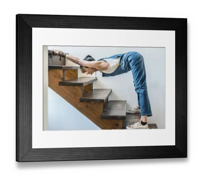 Framed Print : A woman doing stretching exercises on the stairs of her home Framed Print : A woman doing stretching exercises on the stairs of her home